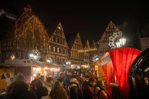 Dense crowds at a Christmas market in a festively illuminated old town, Christmas market Calw,