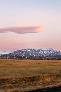 Snow-capped mountains rise majestically under a pastel sky during a serene Icelandic winter sunset.