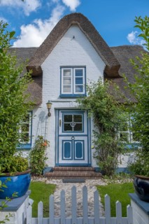 Charming thatched house with white façade, blue entrance area and small garden, Frisian house,