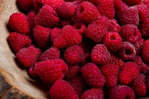 Fresh raspberries in a wooden bowl, food background, concept, food styling, on a dark table, top