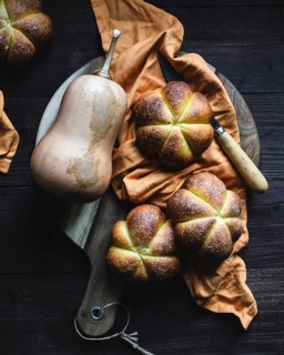 Top view of freshly baked pumpkin bread displayed on a rustic wooden cutting board with an orange