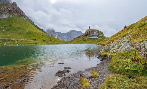 View over the mountain lake Wolayersee to the alpine club hut Wolayerseehütte, cloudy mountain