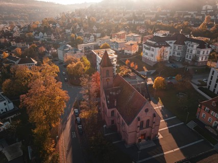 Church in the middle of a town in autumn light with surrounding trees and houses, Nagold, Black
