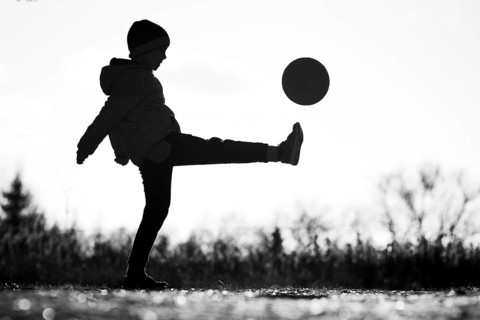 Silhouette of young boy playing football