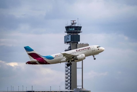 Eurowings Airbus A319-100 taking off at Düsseldorf International Airport, air traffic control tower