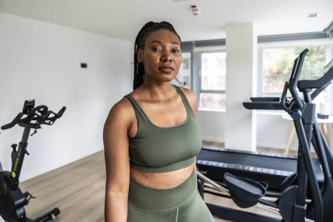 Businesswoman wearing sportswear standing in a hotel gym after a day of work, enjoying a moment of