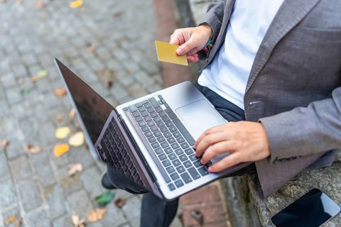 Close-up top view of an unrecognizable businessman using credit card to shop online outdoors