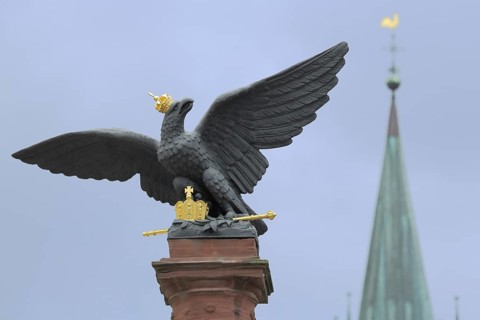 Eagle figure with golden crown and scepter at the war memorial, orphanage square and blurred church