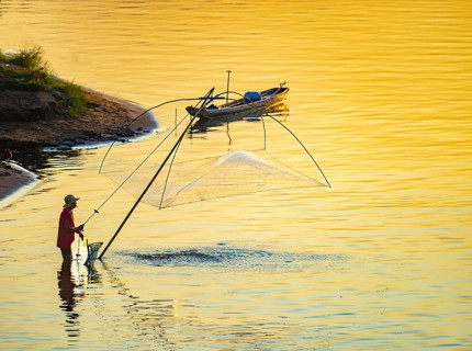 Fisherman with a sinking net at sunset on the Mekong, Luang Prabang, Laos