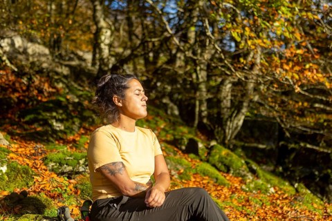 A woman enjoys a rest in the vibrant autumn landscape of Gorbea Natural Park, Basque Country, Spain
