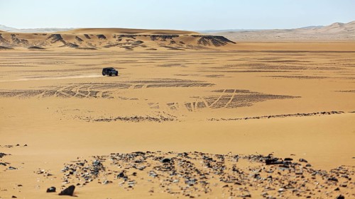 A single vehicle drives through the endless sand dunes of a vast desert, Off-road vehicle through