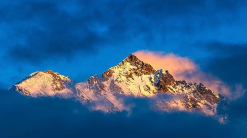 Snow-covered summit of the Weisshorn mountain, illuminated by the evening sun, view from Grimentz,