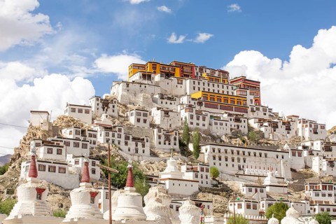 The majestic Thiksey Monastery stands against a backdrop of a bright blue sky in Ladakh, India.
