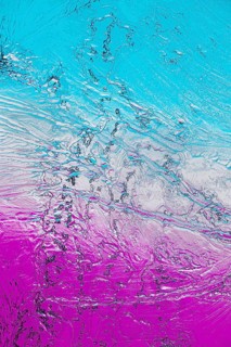 A vibrant close-up of microcrystals viewed under a microscope, featuring bright shades of turquoise