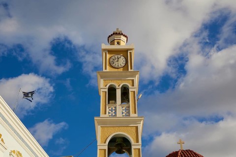 Paraklesio Church, Close-up of a clock tower under a cloudy sky in yellow and white colours,