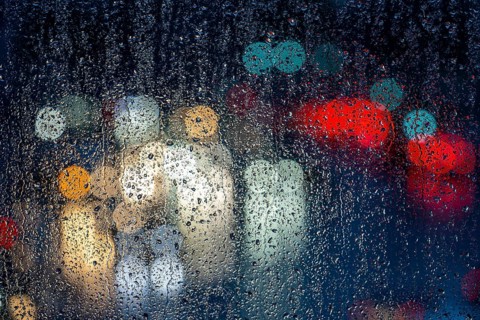 Rainy weather, road traffic, raindrops on a window pane, behind, blurred, lights of vehicles on a