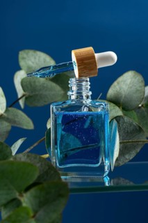 Cooling face serum for men, housed in an elegant glass dropper bottle, accentuated by natural