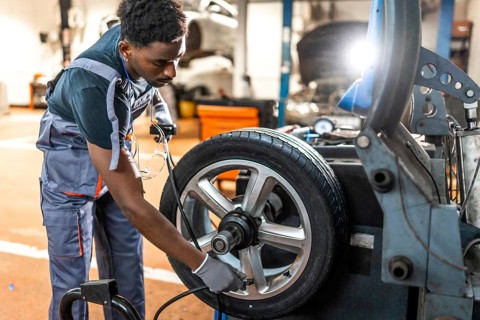 Professional mechanic balancing a car tire on advanced machinery in a modern auto repair shop,