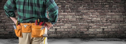 Contractor With Tool Belt Facing Aged Brick Wall Banner