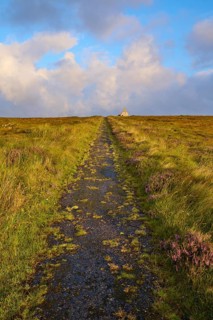 Grassy path leads to a hut under a partly cloudy sky, Moine House, Moine Track, Lairg, Scotland,