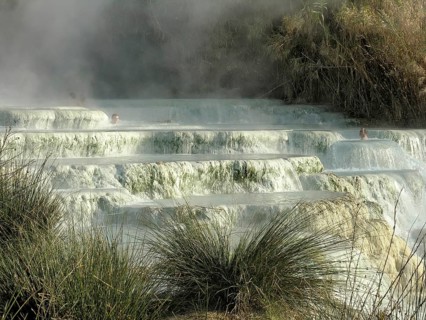 Warm sulphurous thermal springs, travertine waterfalls with clouds of water vapour, sinter, men