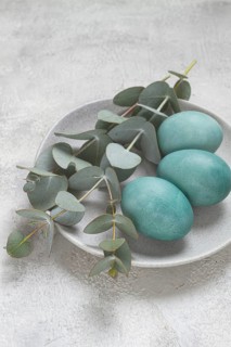 Easter colored eggs, in turquoise tones, on a gray plate, with a branch of eucalyptus, Easter card,