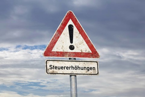 (photo montage) Sign with text TAX INCREASES under a road sign Danger location exempted in front of