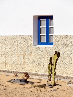 Simple façade, blue window, minimalist front garden, unpaved village street, Caleta del Sebo, La