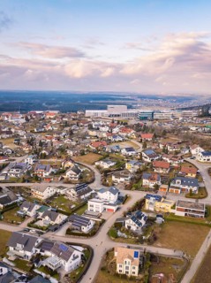 Aerial view of a sprawling suburban neighbourhood with many houses and streets under a cloudy sky,