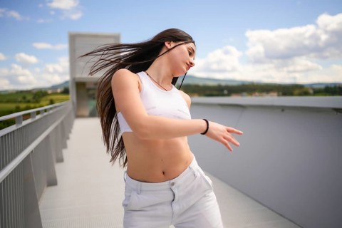 Motion photo of a caucasian young confident young woman dancing urban music on an outdoor bridge