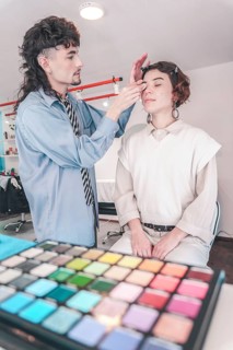 Professional makeup artist carefully applying eyeshadow on model's face using a brush, with a