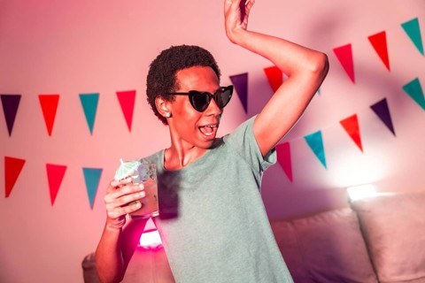 Cool latin man dancing and drinking cocktails partying at night with colorful neon light