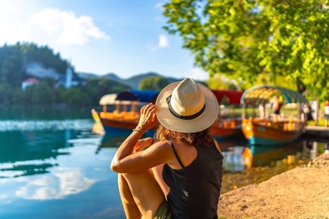 Woman enjoying summer vacation at lake bled, slovenia, with traditional pletna boats and bled