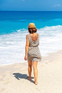 Woman walking along the sea at Megali Petra beach with turquoise water of Lefkada island, Ionian