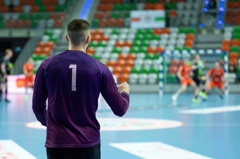 Handball goalkeeper's victory gesture and handball match in the background