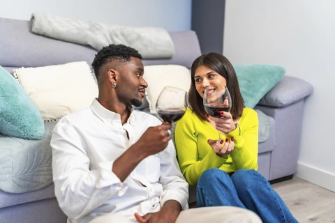 Couple enjoys a moment together, sharing wine and smiles while sitting comfortably at home,