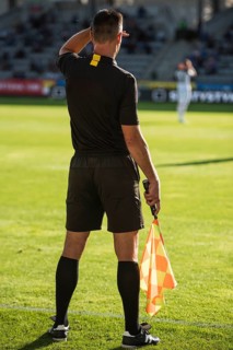 Touchline referee looking against the light during the soccer match.