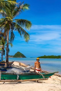 Filipino fisherman working near traditional bangka boats on idyllic lakdayan beach, coron island,