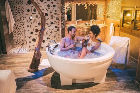 Happy interracial couple relaxed in the jacuzzi enjoying their self and drinking wine