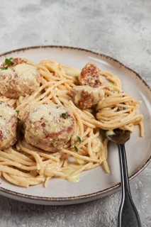 Spaghetti with chicken meatballs, with cream sauce, and parmesan cheese, and decorated with