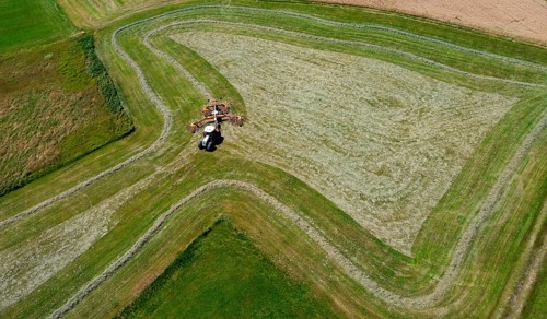 Drone view of a tractor turning hay in the field, Flachgau, Land Salzurg, Austria