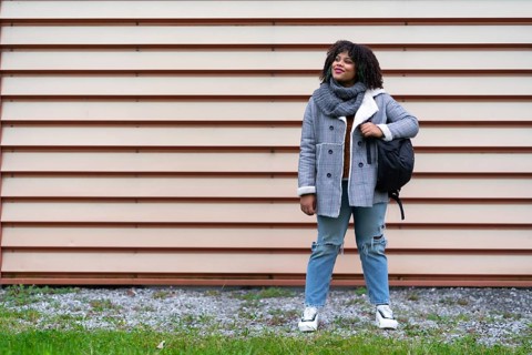 Portrait of black ethnic girl a gray wall in the university, with mochica from school on the back