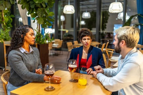 Multi-ethnic diverse coworkers enjoying beer together after work outside a bar at night