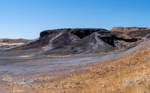 Dry landscape with yellow grass and black volcanic hills, Burnt Mountain, Damaraland, Kunene,