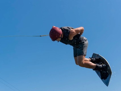 Man does a somersault with wakeboard, water ski and wakepark