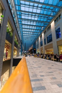 A busy shopping centre with a glass roof and people strolling through the aisles, Berlin, Germany