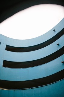 A modern, blue parking lot featuring a multi level circular design enhanced by soft lighting from