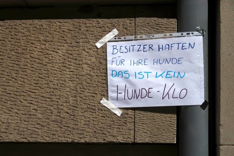 Sign in handwriting, THIS IS NOT A DOG TOILET OWNERS ARE LIABLE FOR THEIR DOGS, house wall, protest