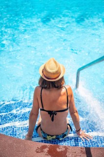Young woman relaxing in pool at spa resort on vacation. Summer relaxing concept