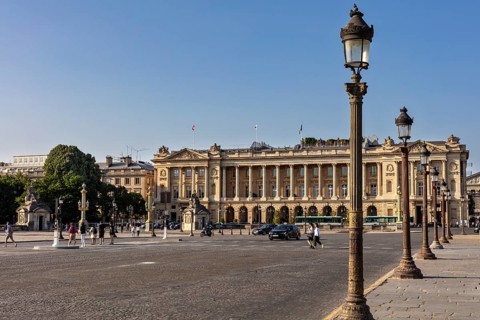 Elegant building on a large square, pedestrians stroll past, a few cars, Paris